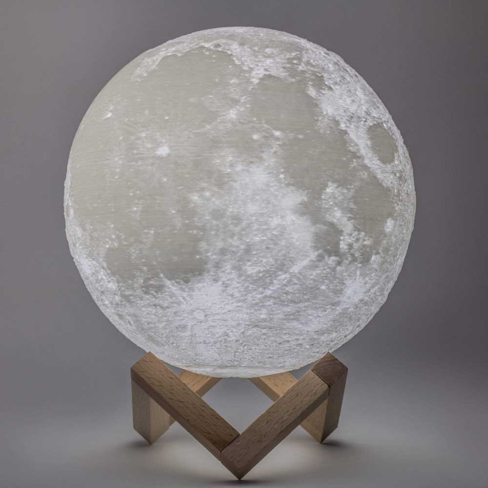 White moon lamp light sphere on wooden tripod base against gray