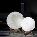 White glowing moon lamp on a small wooden tripod stand