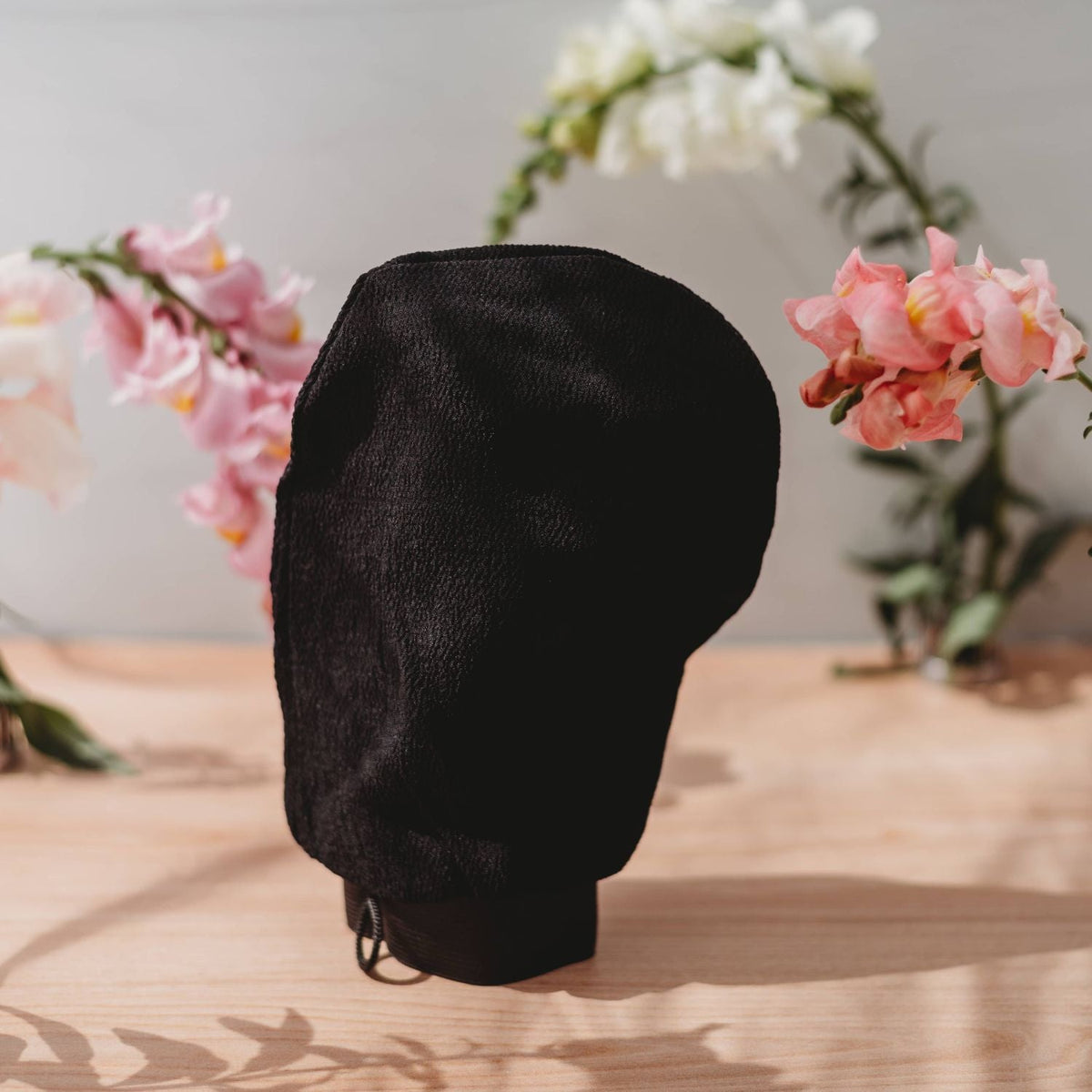 Black self-tanner mitt with drawstring cuff and textured surface
