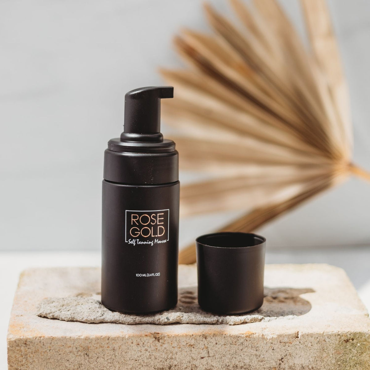 Travel-size self-tanning mousse bottle with pump, open cap, Rose Gold label