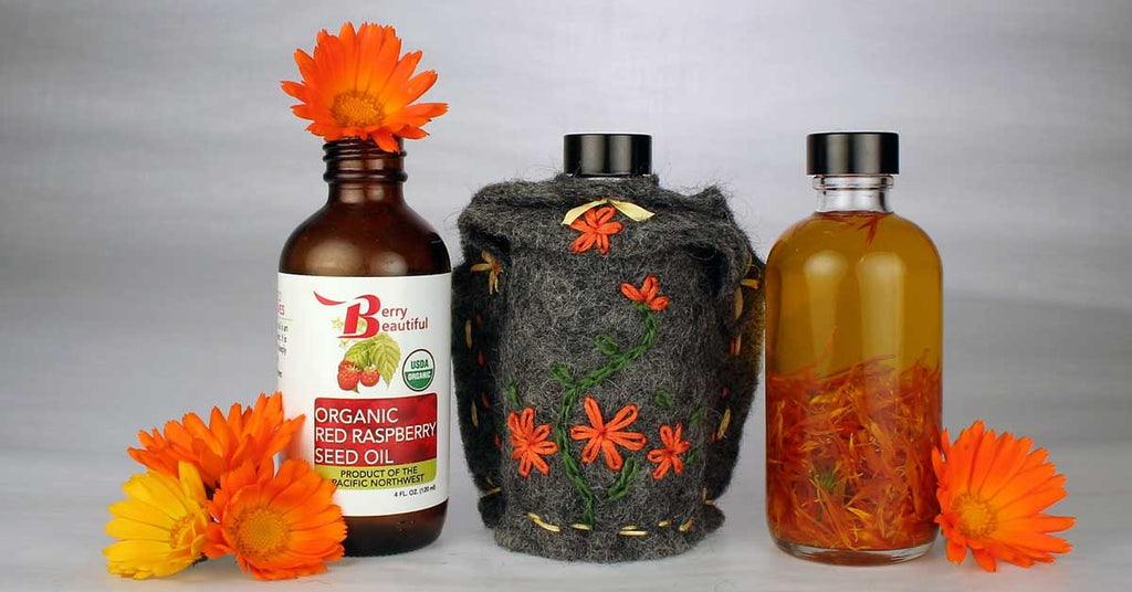 Organic red raspberry seed oil bottles with felt pouch and orange flowers