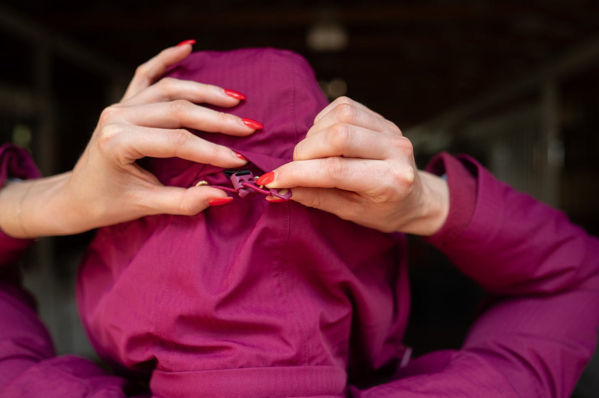 Raspberry insulated jumpsuit chest area with zipper pull as hands adjust it