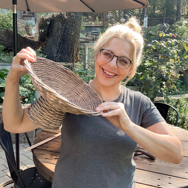 Round woven willow riser basket being held, showing curved woven sides