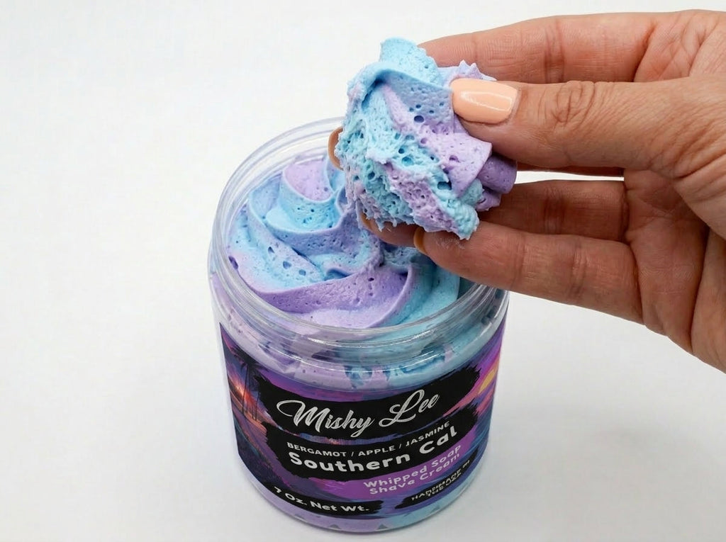 Hand holding a spoonful of purple and blue whipped soap from the jar