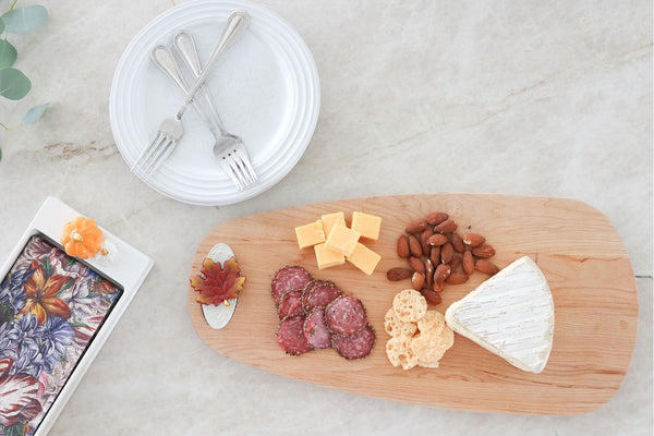 Mini fall leaves ceramic decoration beside cheese, nuts, and sliced board items