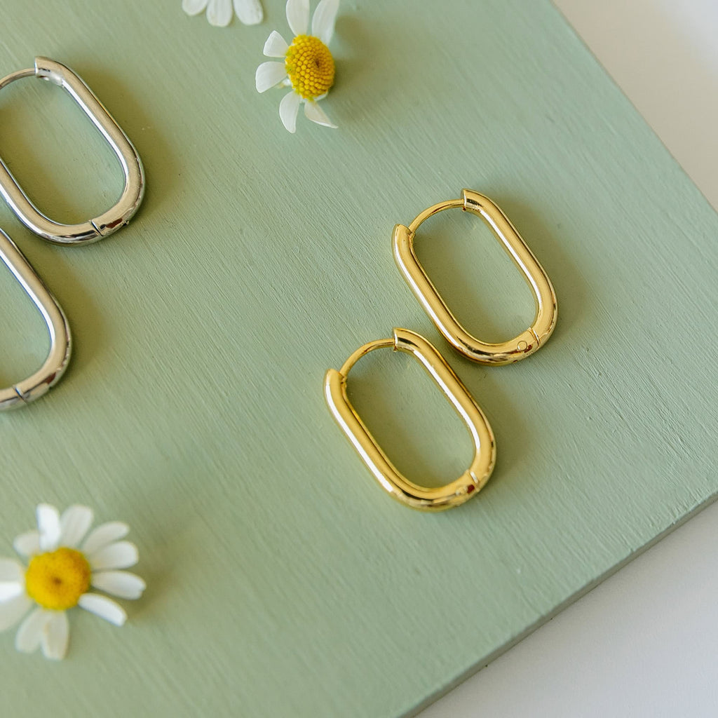 Gold rectangular hoop earrings, two polished hoops on flat surface