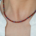 Red beaded necklace with multicolor seed beads, sits at collarbone.