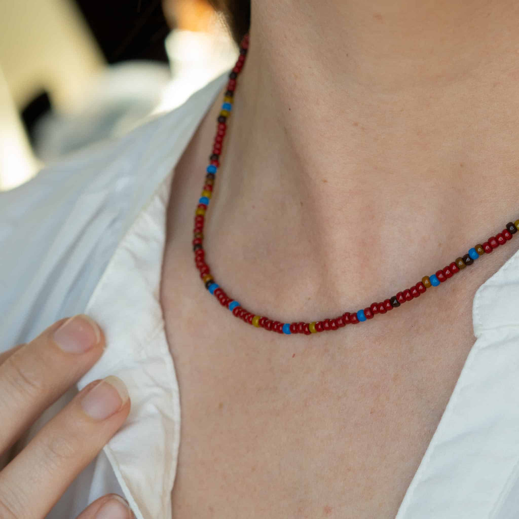 Multicolor beaded necklace on neckline, red and blue bead pattern.