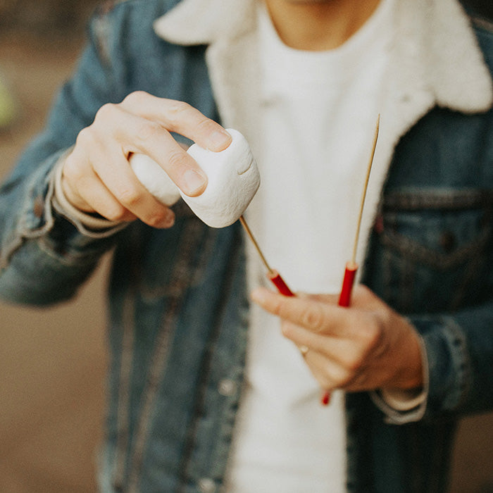 White-tipped skewer held in hand for roasting food over heat