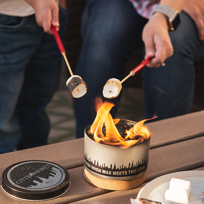 Two red reusable skewers roasting marshmallows over a small flame burner