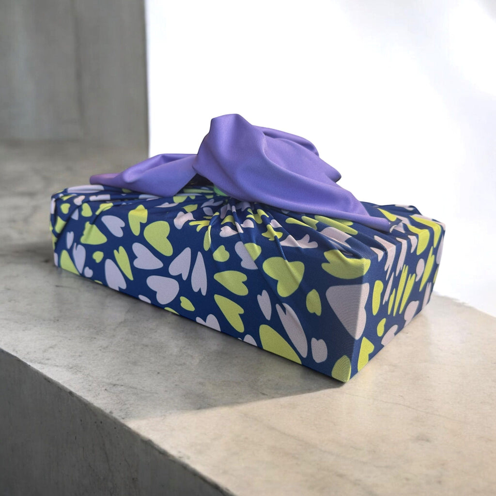 Navy and green leaf-pattern reusable furoshiki wrap with purple knotted top