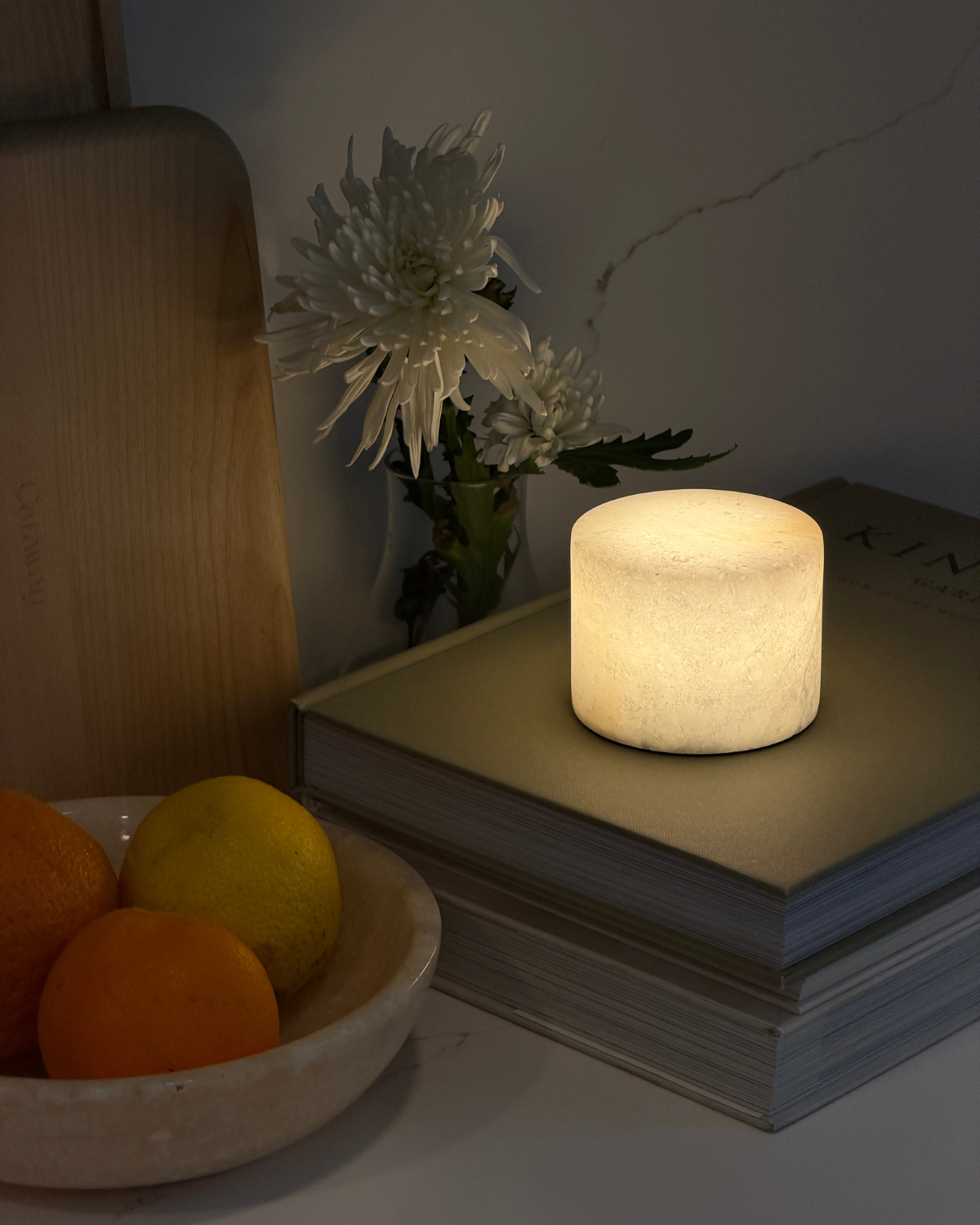 Cylindrical portable lamp with warm glow, on stacked books