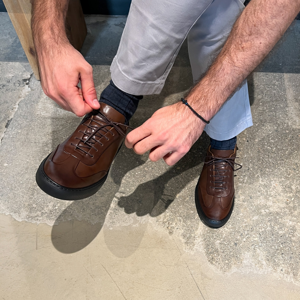 Brown leather lace-up oxford shoes with laces being adjusted