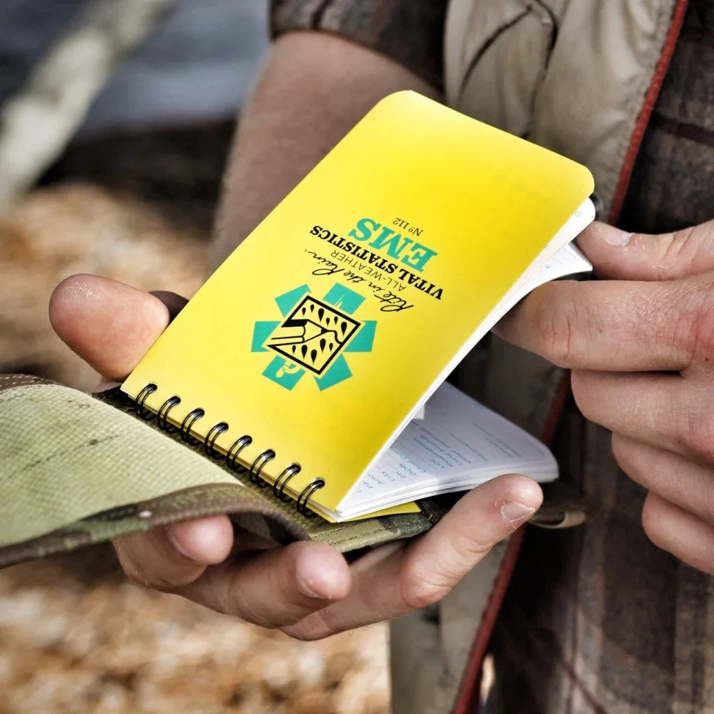 Yellow Rite In The Rain notebook cover with spiral notebook, held open in hands