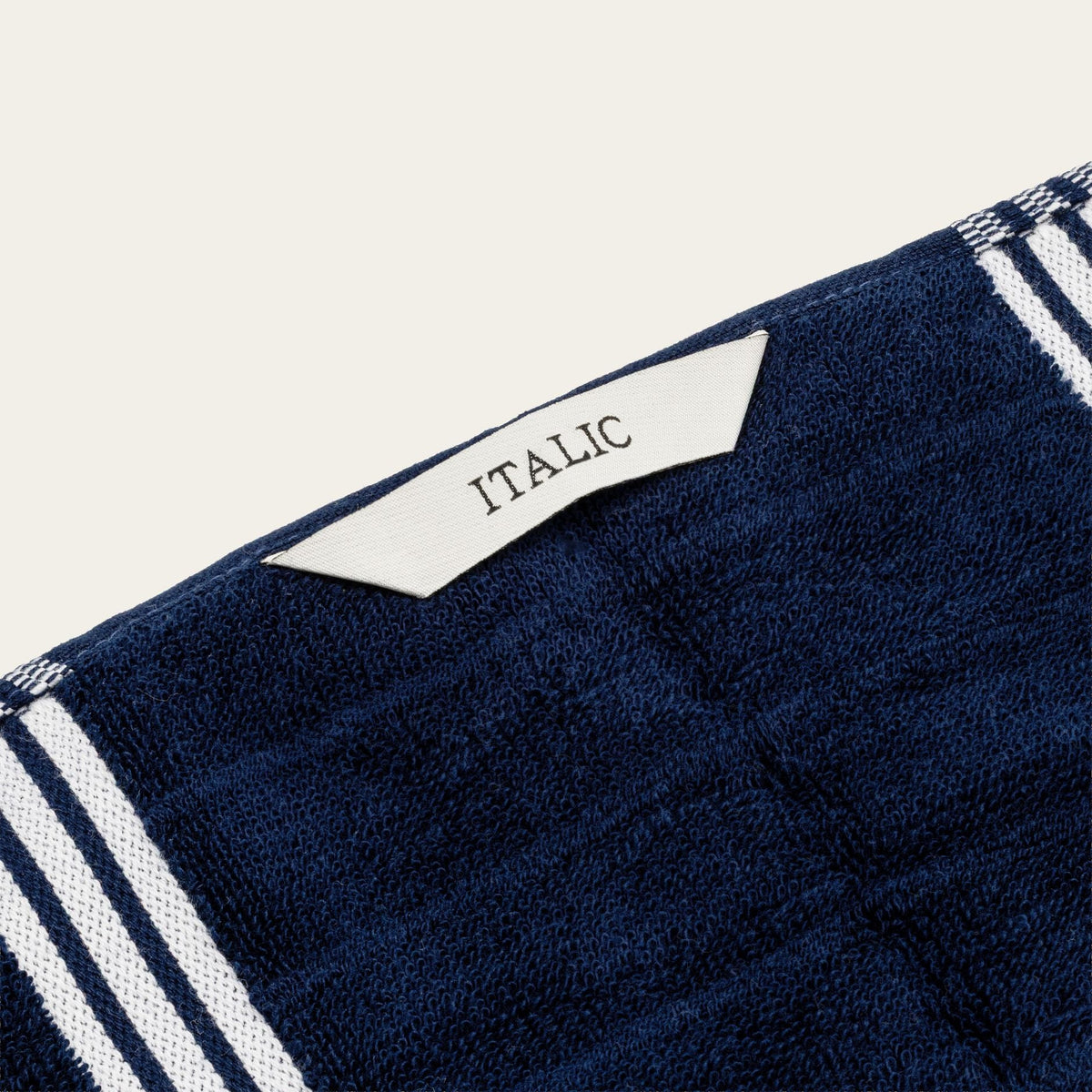 Navy cotton towel corner with woven label and white stripe trim
