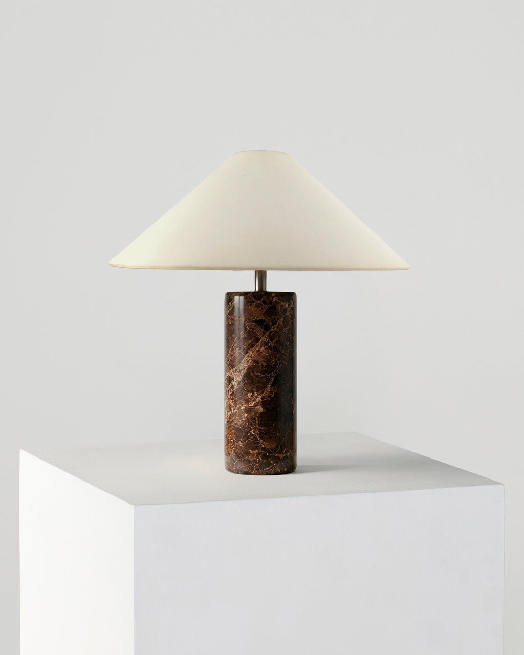 Table lamp with cream fabric shade and dark brown marble cylindrical base.
