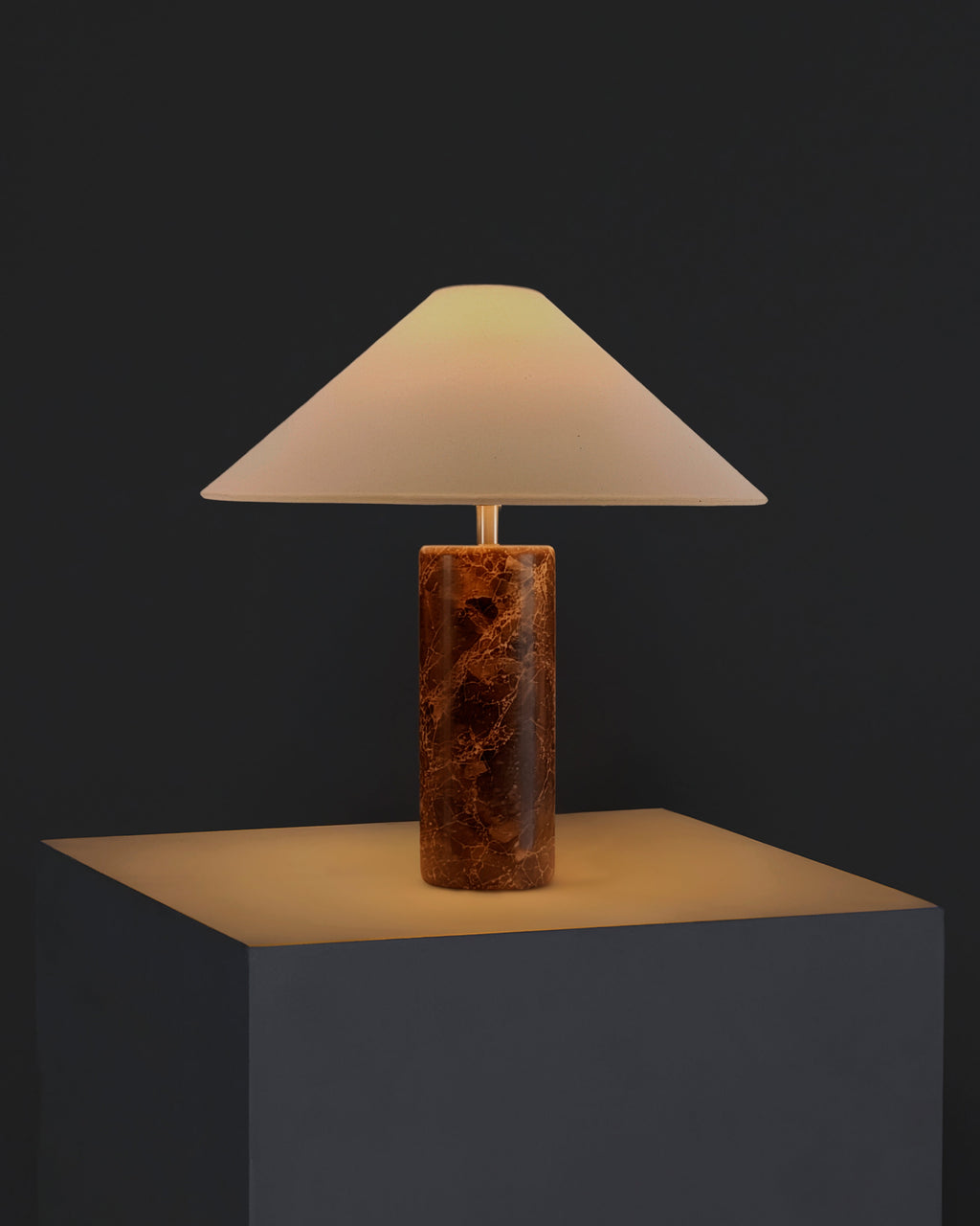 Table lamp with cream fabric shade and warm brown marble cylindrical base.