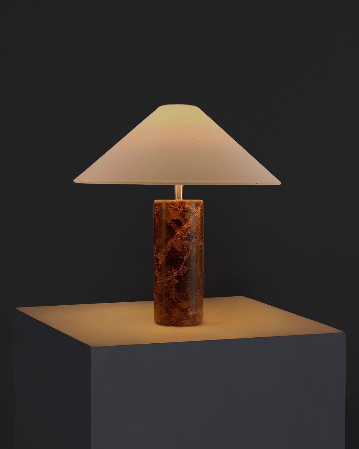 Table lamp with cream fabric shade and warm brown marble cylindrical base.