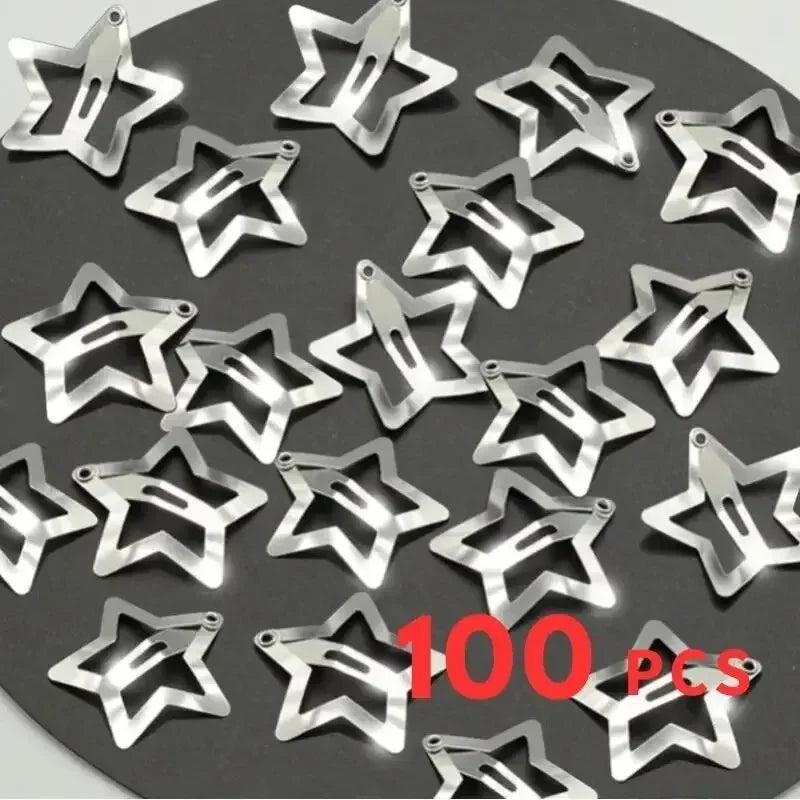 Silver star metal hair clips laid out on a dark tray, visible snap clasps.
