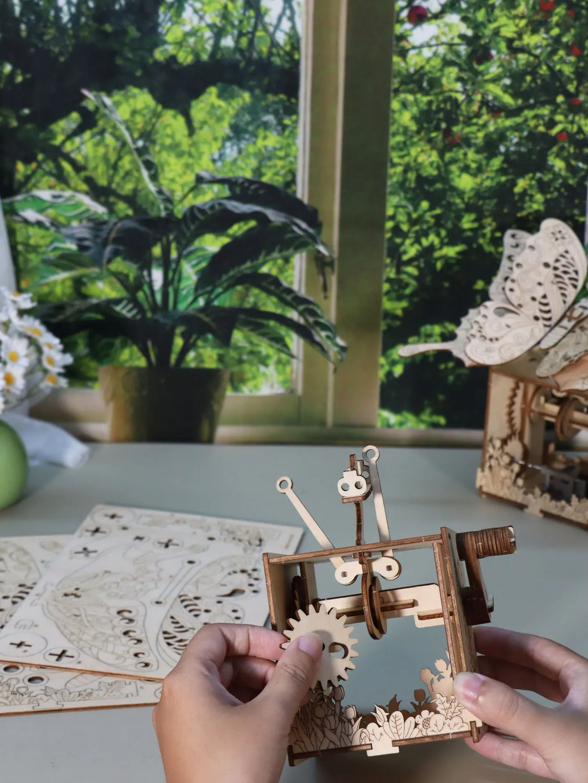 Hands assembling a wooden butterfly music box DIY puzzle kit with wing pieces