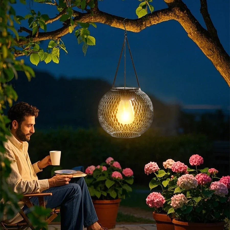 Hanging solar LED lantern with mesh globe and warm amber light, for outdoor decor
