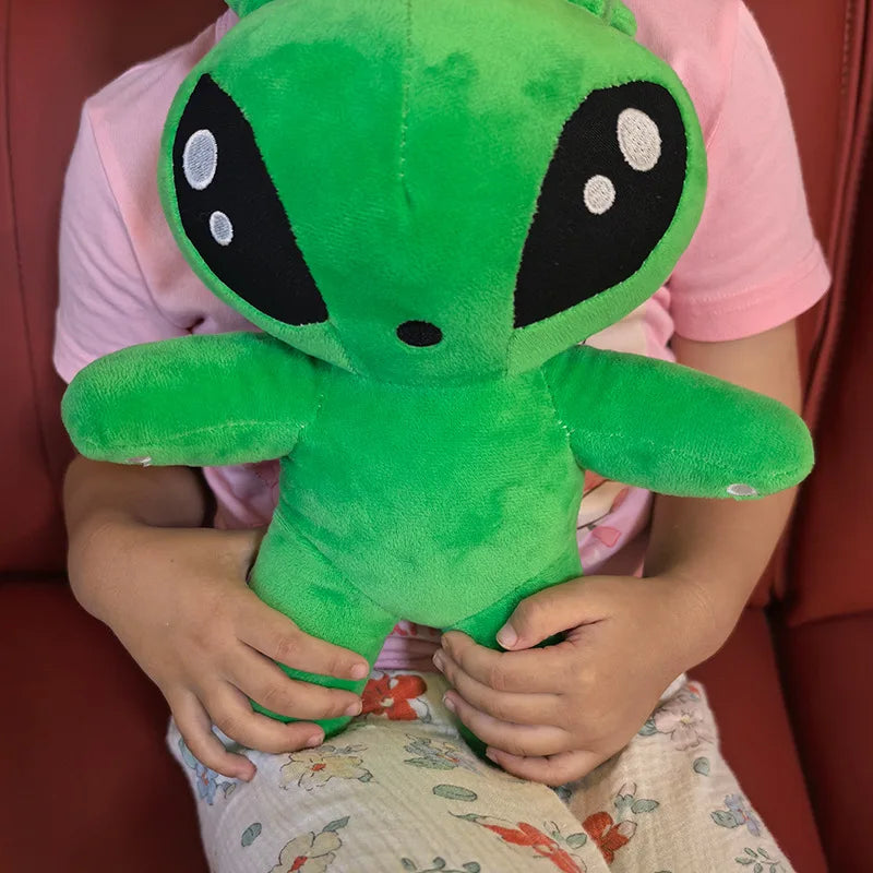 Close-up green alien plush toy face with horn tentacles and black eye panels