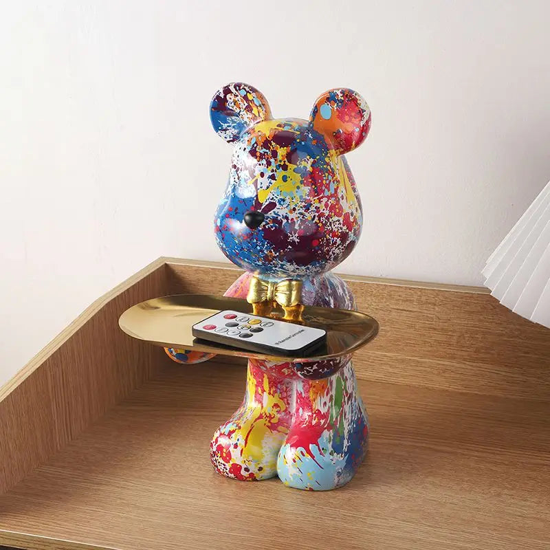 Blue, yellow, and red speckled resin bear organizer with gold tray holding a phone