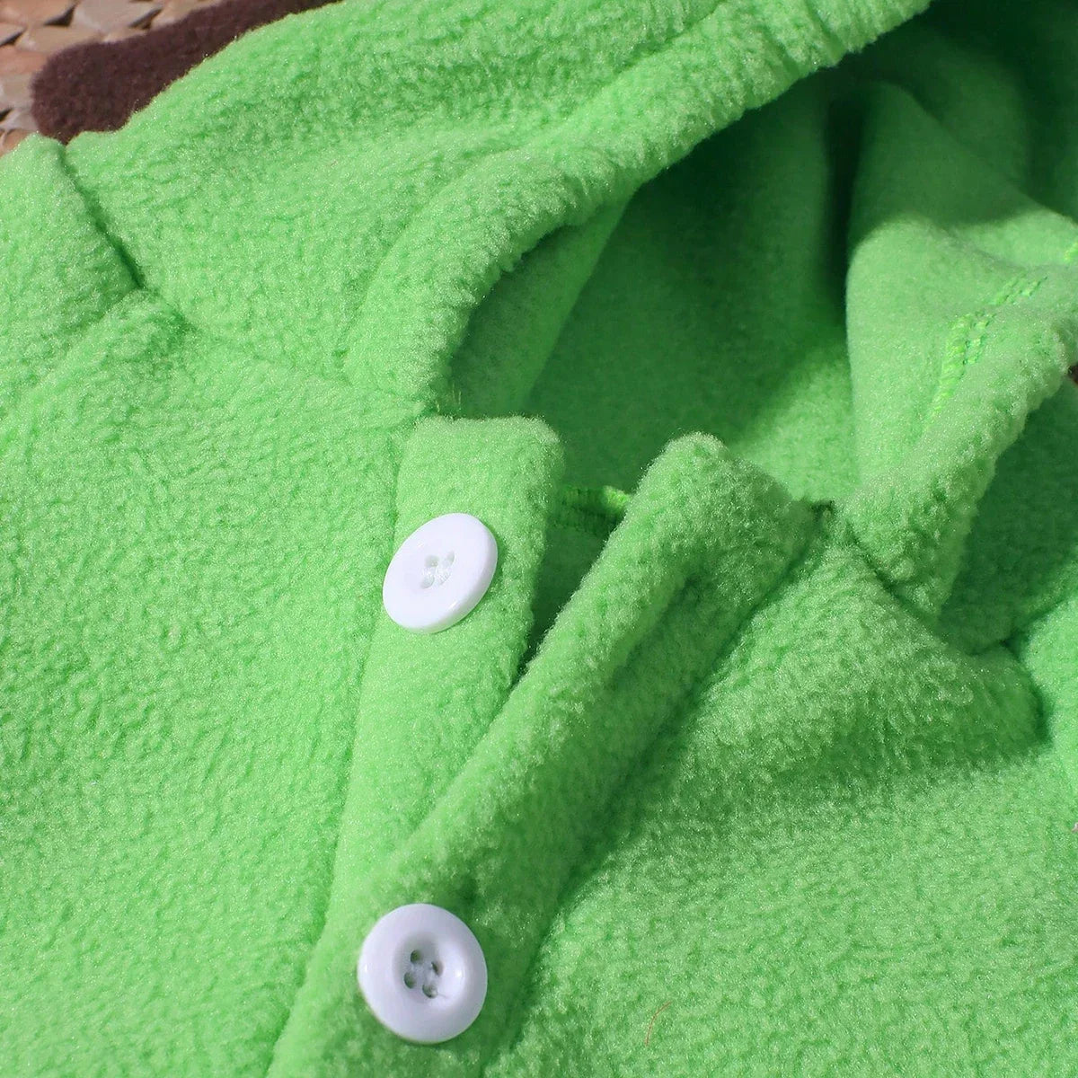 Green plush dinosaur jumpsuit close-up with button placket
