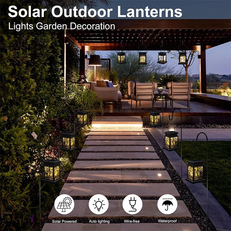 Black solar outdoor lanterns hung along a garden path, emitting warm light