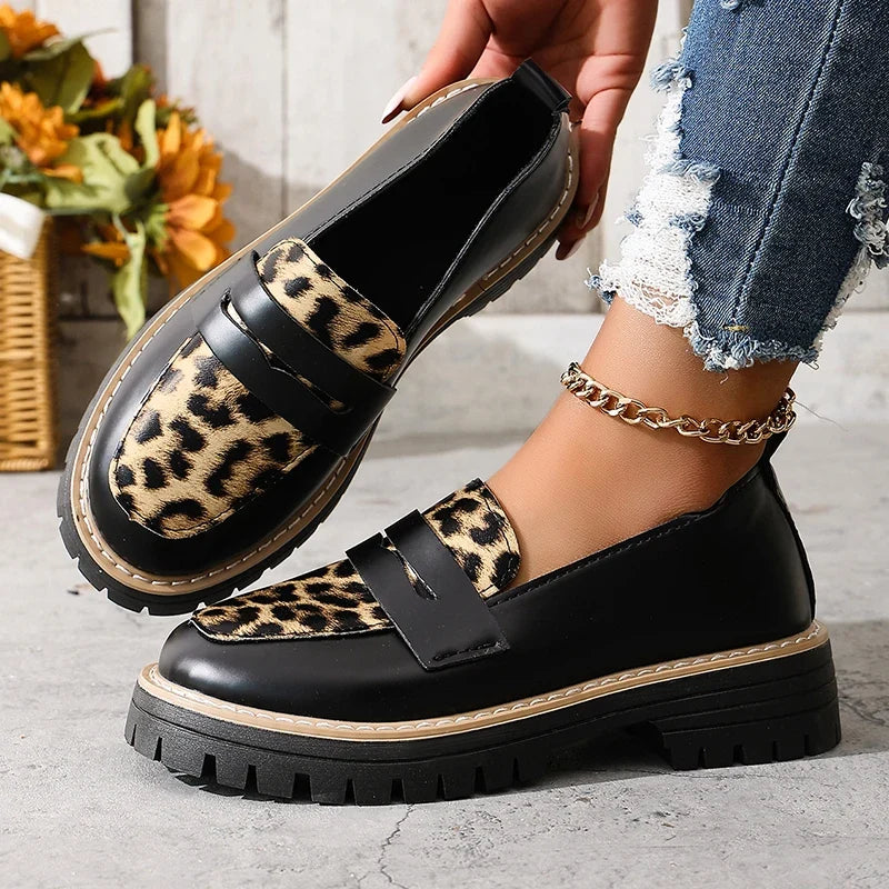 Black slip-on platform loafers with leopard print strap panel and thick sole.