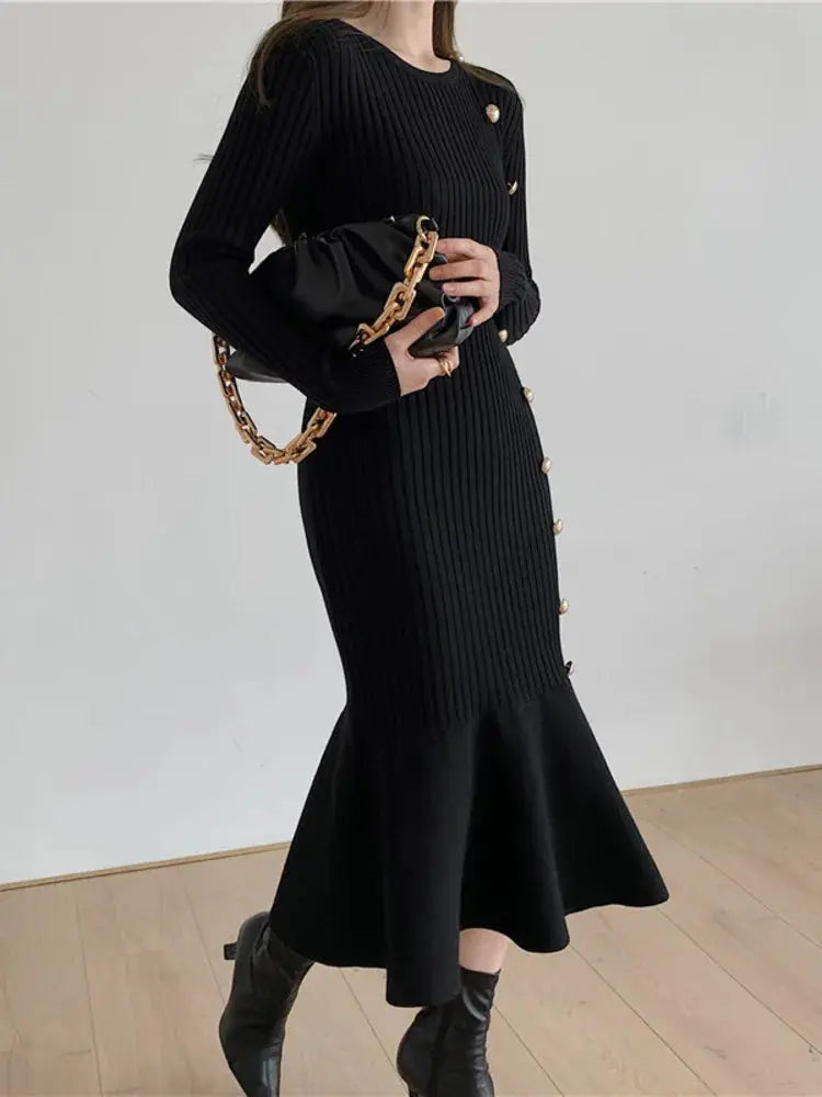 Black ribbed knit sweater dress with long sleeves, gold button details, and flared skirt hem.