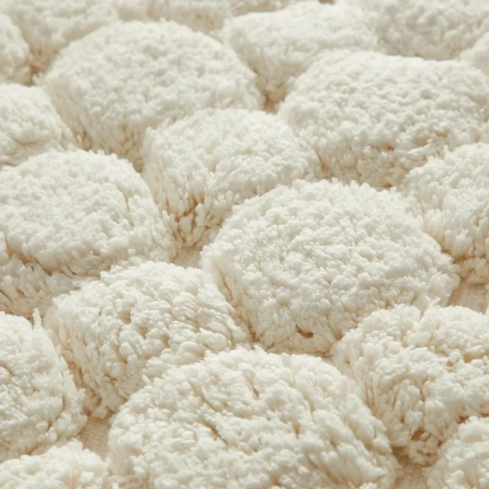 Ivory bath rug with dense shaggy loops and pebble-like raised texture close-up