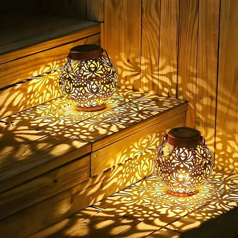 Two bronze iron solar lanterns with carved globe cutouts, warm light glow