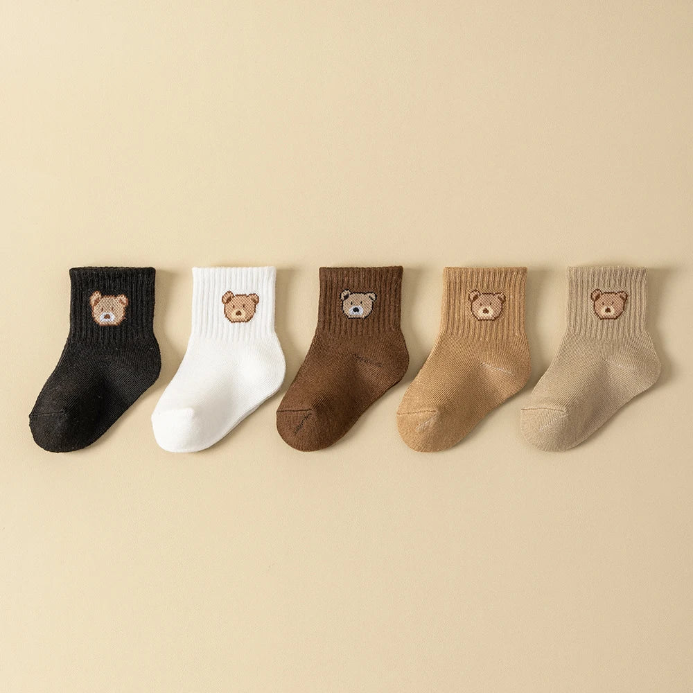 Assorted baby socks with cartoon bear faces, ribbed cuffs in black, white, brown, tan, cream