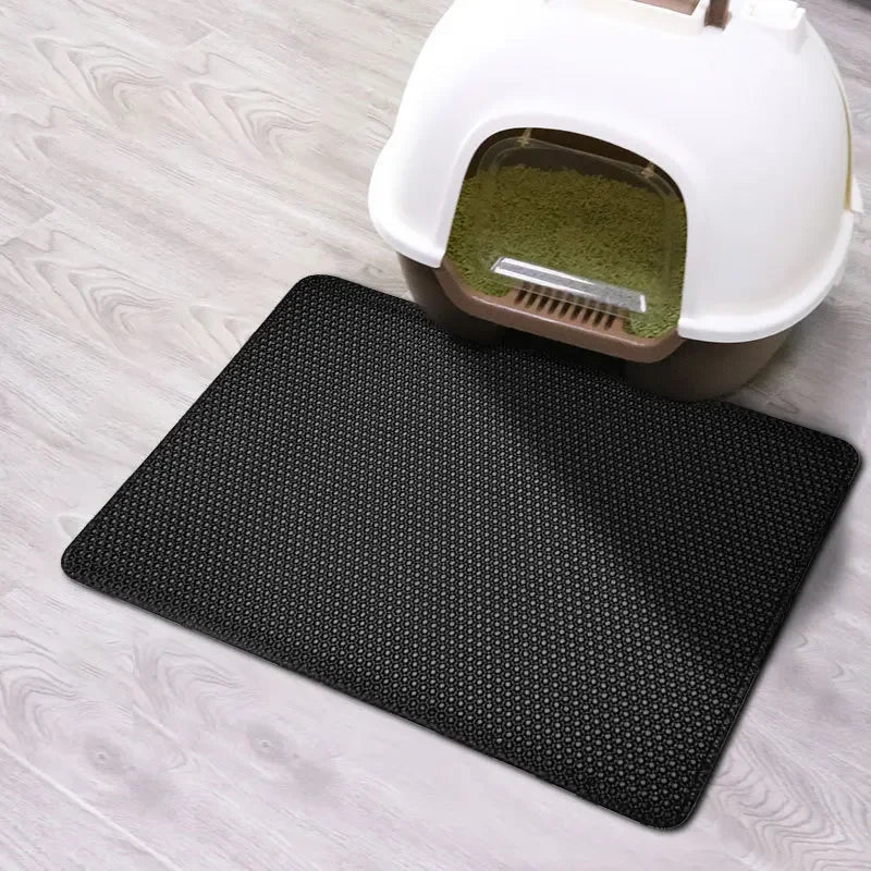 Black cat litter mat with hex grid surface placed under a white litter box