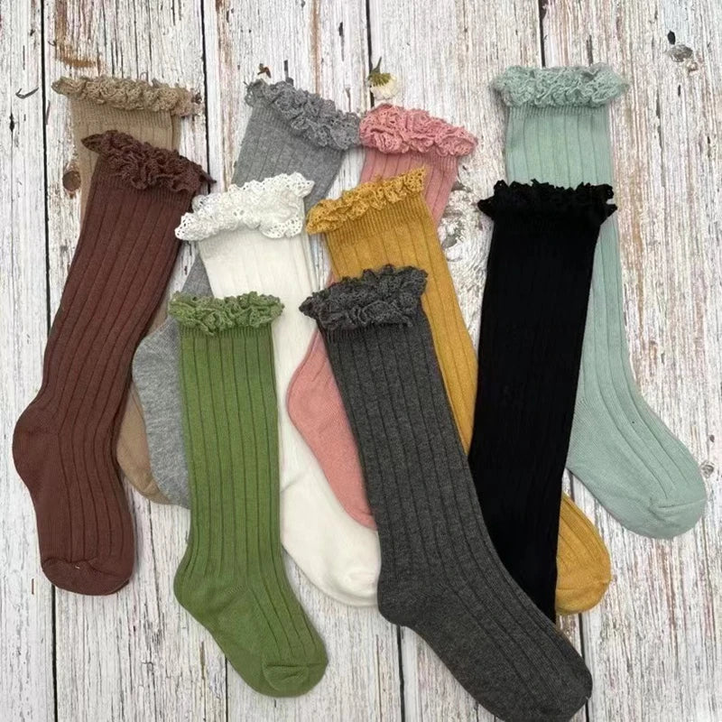 Assorted knee-high socks with ruffled lace cuffs in multiple colors, laid flat