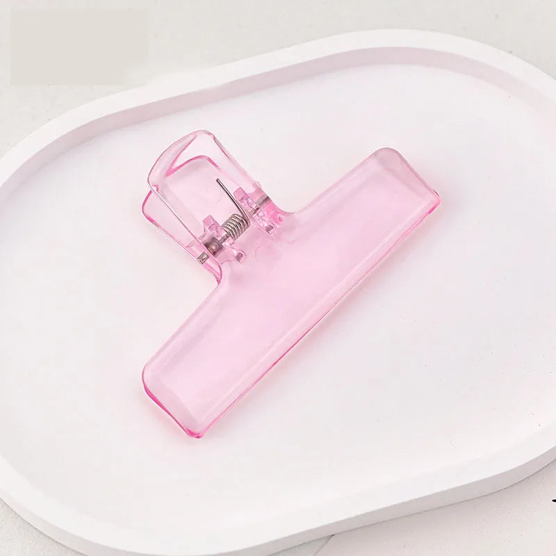 Pink ice jelly clip with transparent acrylic body and spring clasp on tray