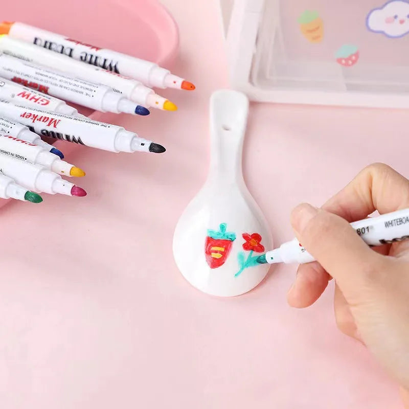 Hand using a water floating ink marker to draw on a white ceramic spoon