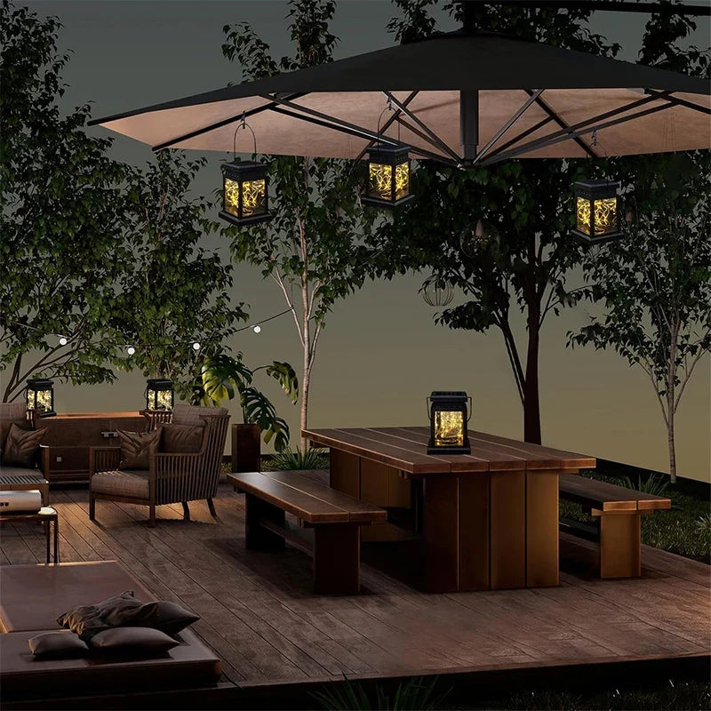 Black solar hanging lanterns with glowing windows, suspended above outdoor patio furniture