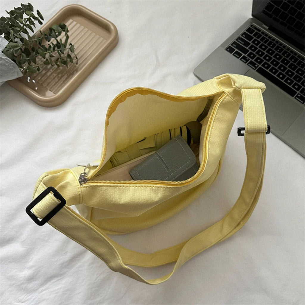 Yellow crossbody bag with puppy pendant, open top, and adjustable shoulder strap