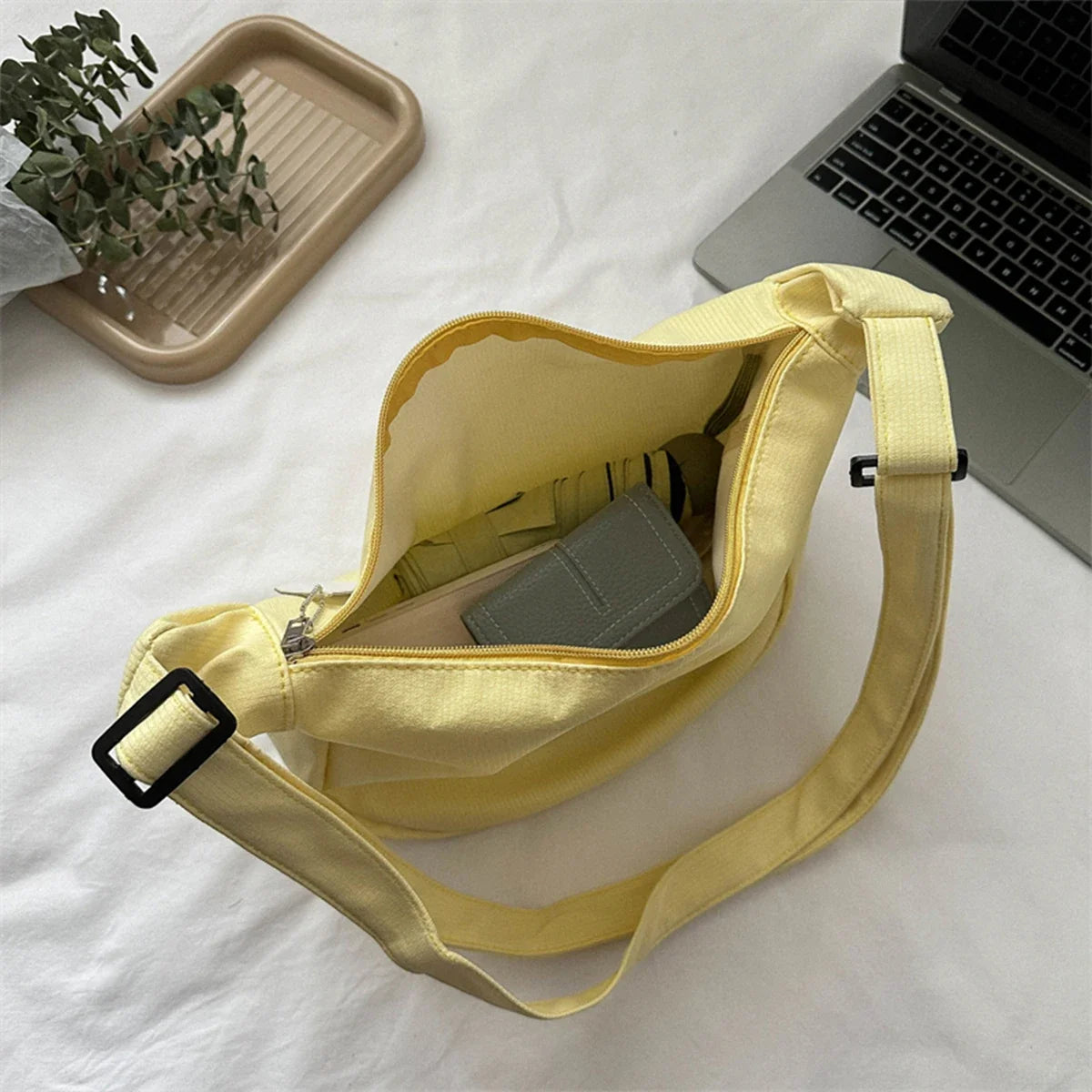 Yellow crossbody bag with puppy pendant, open top, and adjustable shoulder strap