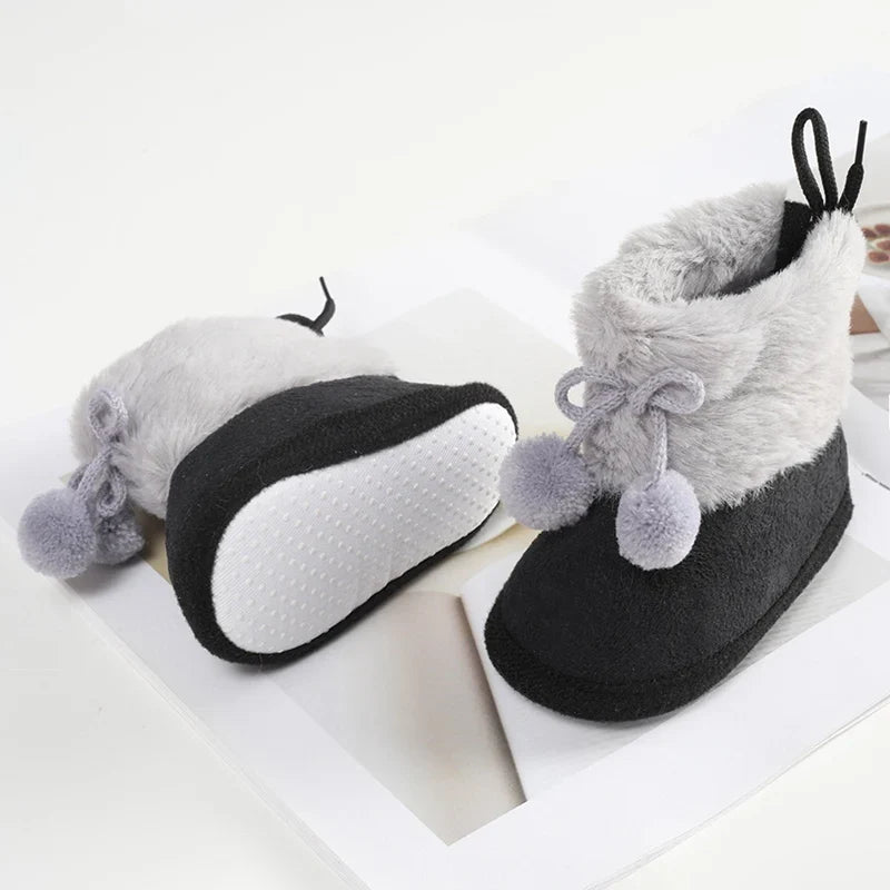 Baby plush winter booties with bow laces, pompom accents, and soft sole; gray and black