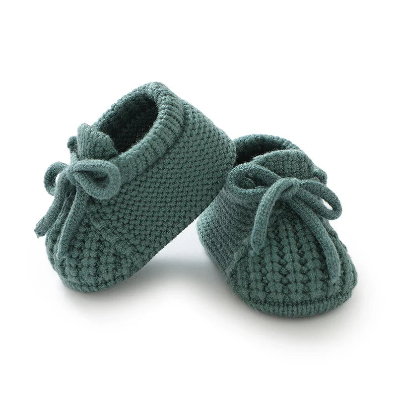 Deep teal knitted baby booties with tie lace bows and textured knit