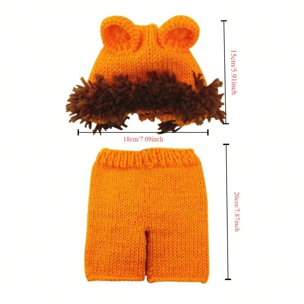 Lion-themed knitted infant set: orange hat with ears and brown fringe, orange shorts
