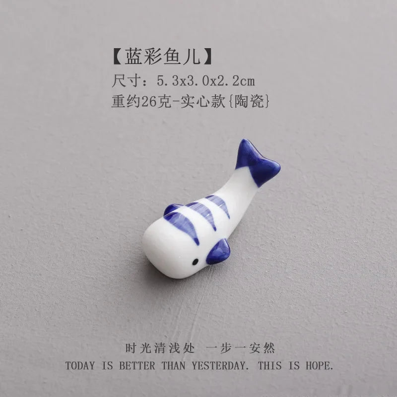 White ceramic fish chopstick holder with blue stripes, small fin tail utensil rest
