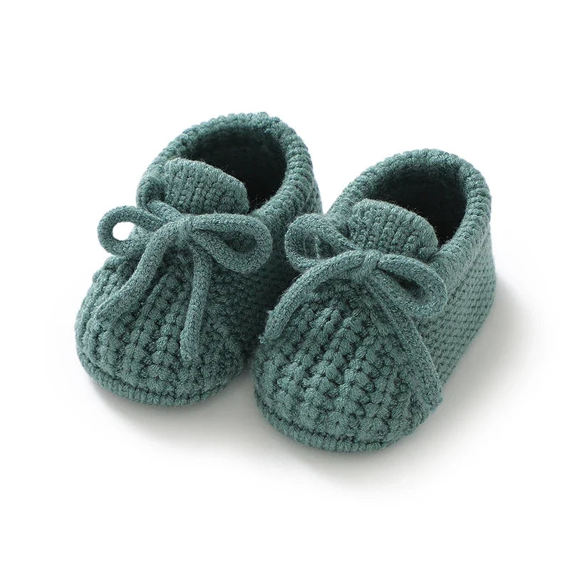 Teal knitted baby booties with soft lining and tie lace bows