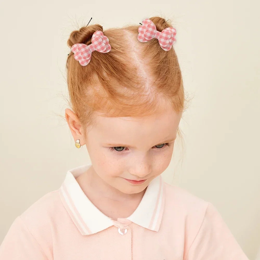 Two pink gingham bowknot hair clips on a girl's ponytail