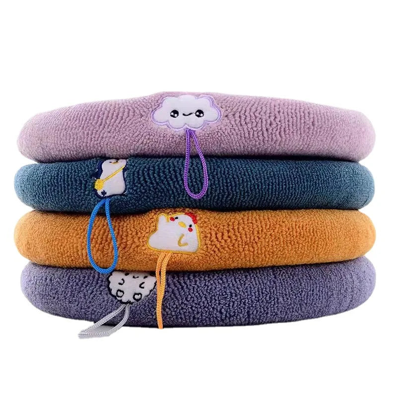 Stack of plush toilet seat cover mats in multiple colors with handle cords