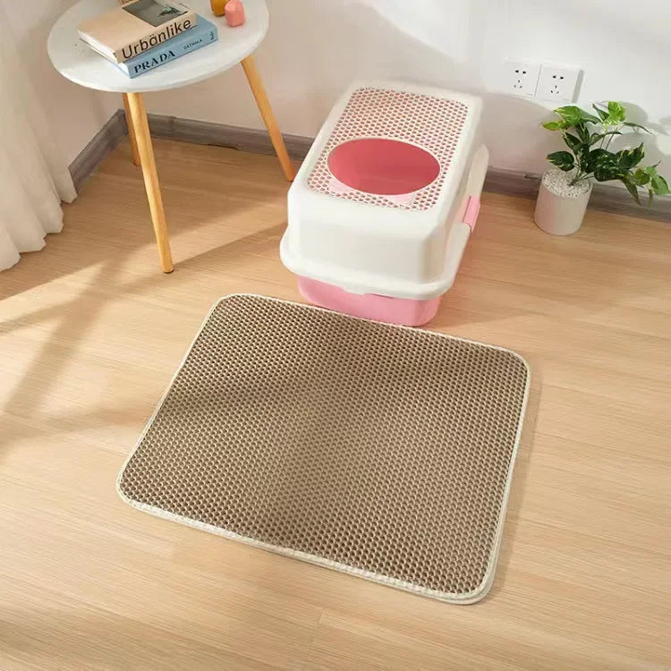 Gray cat litter mat with hex-pattern grid beneath a pink-and-white litter box