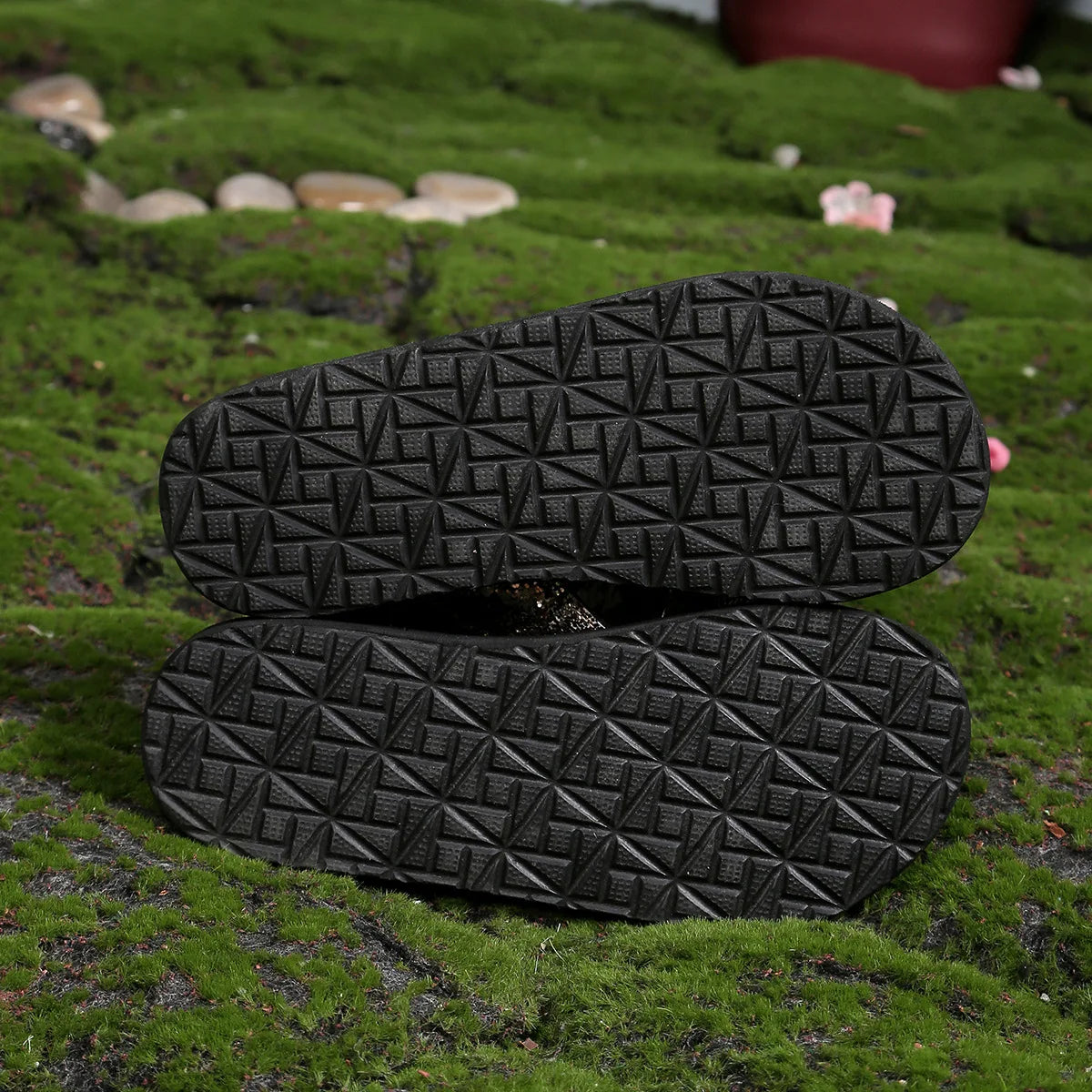 Black textured outsole view of platform sandals with tread pattern.